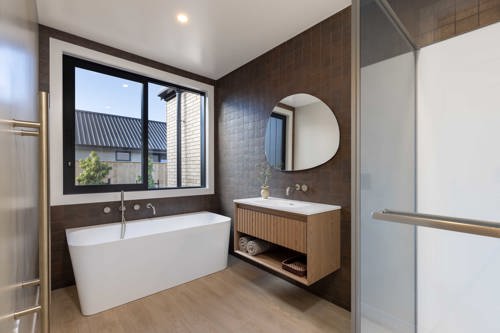 Ensuite bathroom with freestanding bath and travertine tile, David Reid Homes Nelson show home Richmond