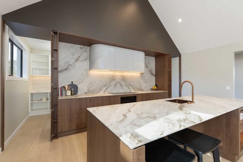 Custom kitchen with curved rangehood, Tahoe Walnut cabinetry and porcelain benchtop – David Reid Homes Nelson show home Richmond